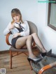 A woman sitting on a chair wearing black stockings and high heels.