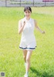 A woman in a white shirt and blue skirt running in a field.