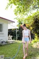 A woman standing in the grass with a hose.