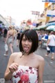 A woman in a floral dress holding a lollipop in her mouth.