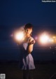 A woman in a blue and white dress holding sparklers.