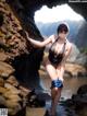 A woman in a black bathing suit standing in the water.