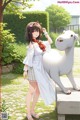 A girl in a white dress standing next to a white sheep.