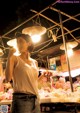 A woman standing in front of a food stand at night.