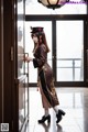 A woman in a brown dress and hat standing in front of a door.