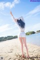 A woman standing on a beach with her arms outstretched.