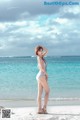 A woman in a white bathing suit standing on a beach.