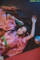 A woman in a pink kimono laying on a red couch.