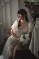 A woman in a wedding dress sitting on a chair.