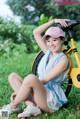 A woman sitting on the grass next to a yellow bike.