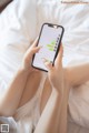 A woman sitting on a bed holding a cell phone.