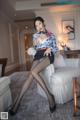 A woman sitting on a white couch in a living room.