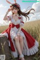 A woman in a red and white dress sitting on a tree stump.