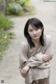 A woman in a beige dress sitting on a dirt road.