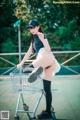 A woman sitting in a shopping cart on a tennis court.