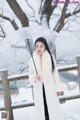 A woman standing in the snow holding an umbrella.