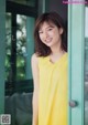 A woman in a yellow dress standing in front of a door.